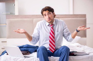 Evde yatakta oturup genç çalışan 