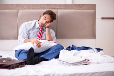 Evde yatakta oturup genç çalışan 