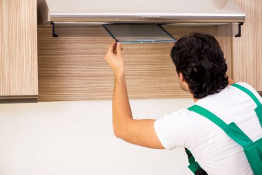 Young contractor repairing air-conditioner in kitchen clipart