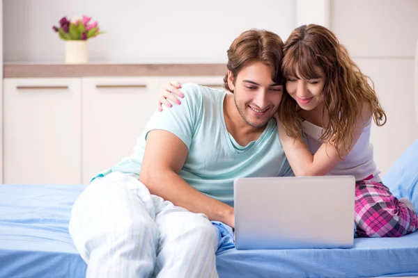 Молода пара з ноутбуком в спальні — стокове фото