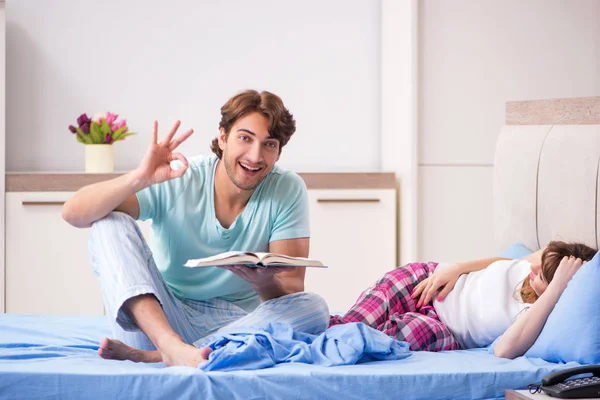 Unga par med bok i sovrummet — Stockfoto