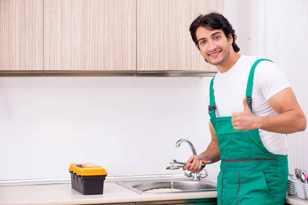 Jovem canalizador torneira de reparação na cozinha — Fotografia de Stock