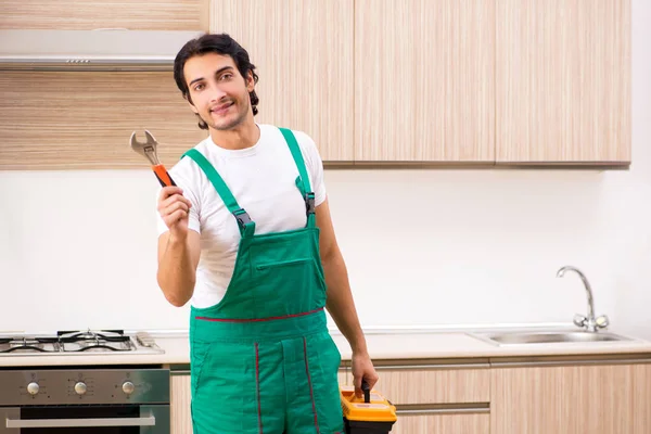 台所でオーブンを修理する若い請負業者 — ストック写真