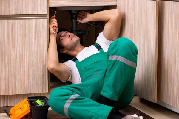 Joven fontanero reparando lavabo en la cocina — Foto de Stock