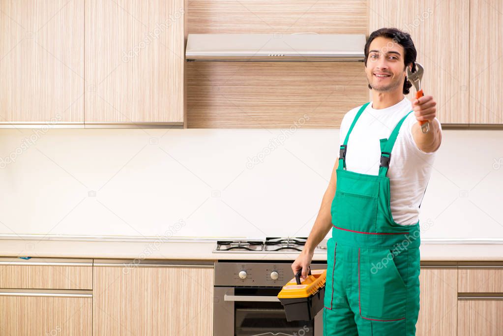 Young contractor repairing oven in kitchen 