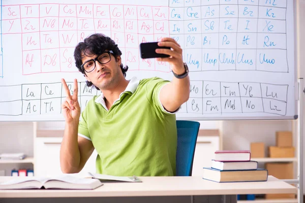 Молодий студент-хімік перед періодичною таблицею — стокове фото