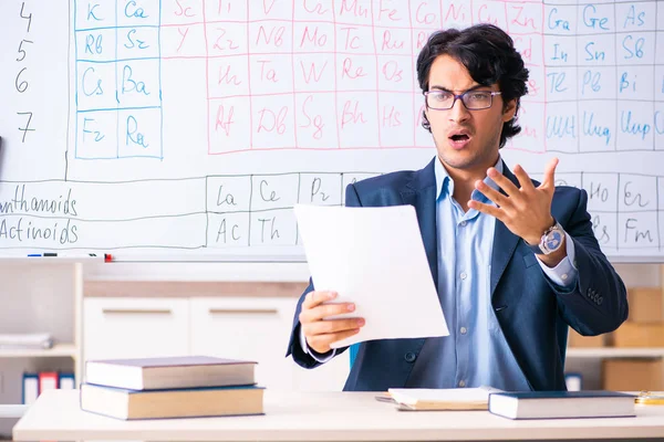 Joven profesor de química masculino delante de la tabla periódica — Foto de Stock