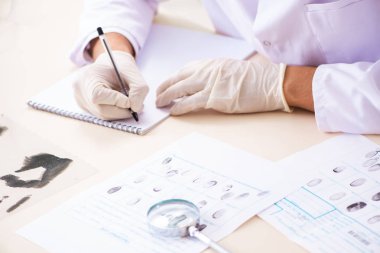 Adli tıp uzmanı laboratuardaki parmak izlerini inceliyor.