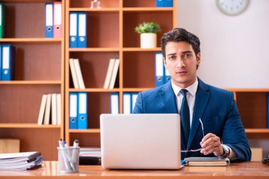 Genç yakışıklı işadamı ofiste çalışıyor.