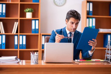 Genç yakışıklı işadamı ofiste çalışıyor.