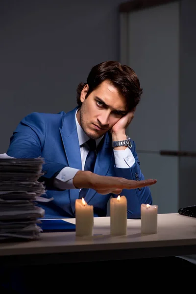 Businessman working late in office with candle light