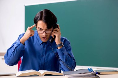 Tahtanın önünde genç bir erkek öğretmen.  