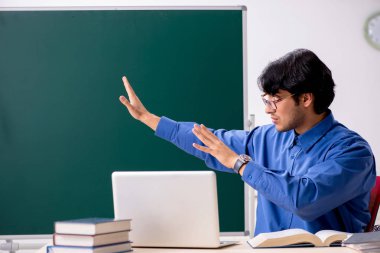 Tahtanın önünde genç bir erkek öğretmen.  