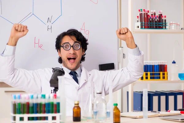 Joven químico divertido delante de la pizarra blanca — Foto de Stock