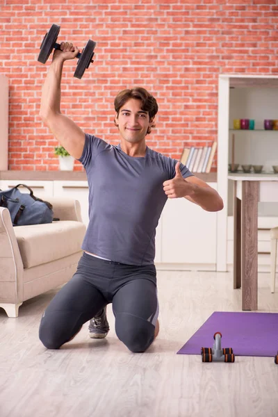 Joven hombre guapo haciendo ejercicios deportivos en casa —  Fotos de Stock