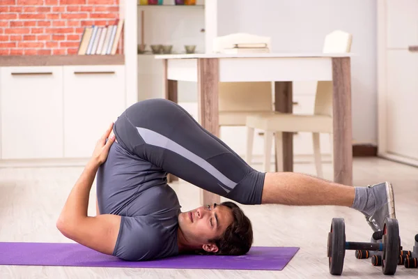 Joven hombre guapo haciendo ejercicios deportivos en casa —  Fotos de Stock