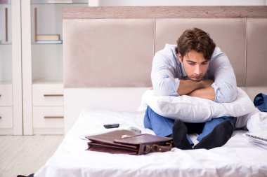 Evde yatakta oturup genç çalışan 