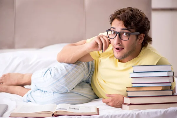 Jonge student studeert in bed voor examens — Stockfoto