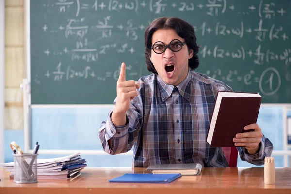 Young funny math teacher in front of chalkboard