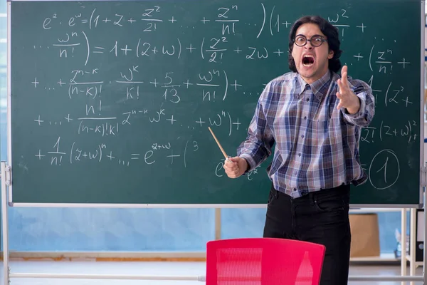 Joven profesor de matemáticas divertido delante de pizarra — Foto de Stock