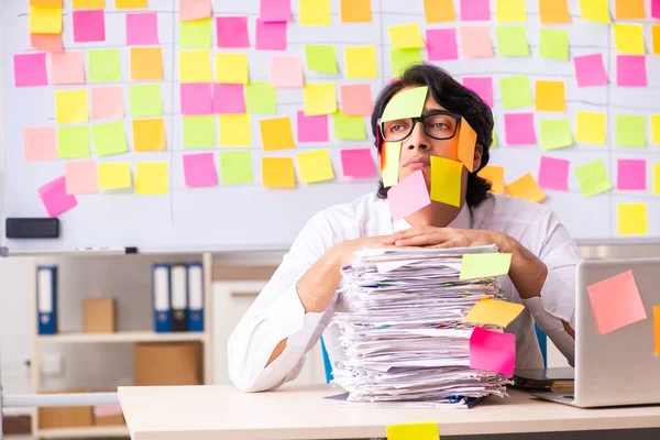 Jonge werknemer in tegenstrijdig prioriteitsconcept — Stockfoto