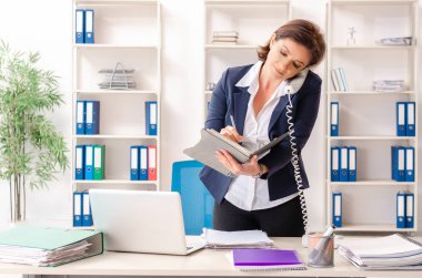 Ofiste oturan orta yaşlı kadın işçiye  