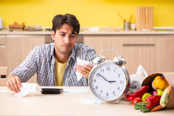 Jovem calculando despesas para legumes na cozinha — Fotografia de Stock