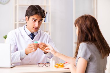 Genç bir kadın, erkek doktor göz doktorunu hastanede ziyaret ediyor.