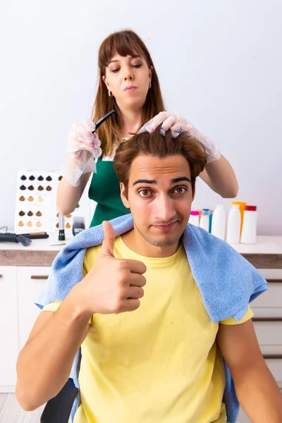 Vrouw kapper aanbrengen van kleurstof op man haar — Stockfoto