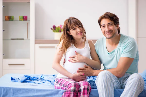 Mujer embarazada con marido en el dormitorio — Foto de Stock