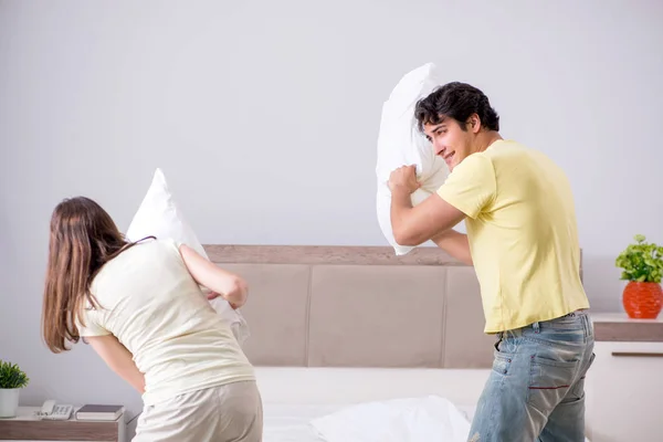 Esposa y marido teniendo pelea de almohadas en el dormitorio — Foto de Stock