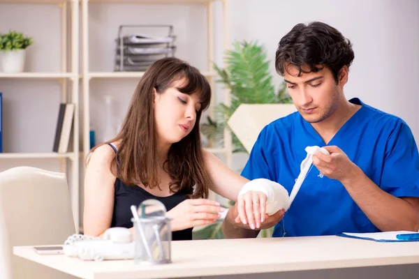 Young woman with bandaged arm visiting male doctor traumotologis — Stock Photo, Image