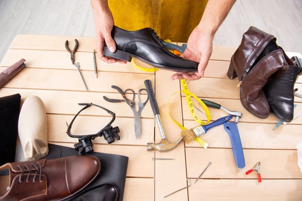 Joven reparando zapatos en taller — Foto de Stock