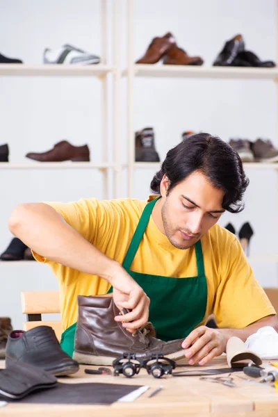 Joven reparando zapatos en taller — Foto de Stock