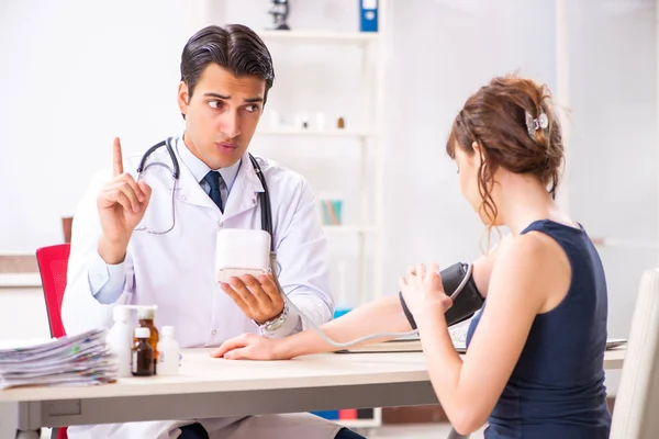 Médico joven revisando la presión arterial de las mujeres — Foto de Stock