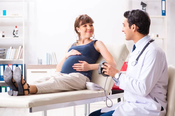 Jovem médico verificando a pressão arterial das mulheres grávidas — Fotografia de Stock