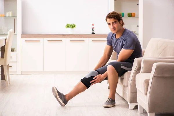 Mladý muž se zraněným kolenem zotavuje doma — Stock fotografie