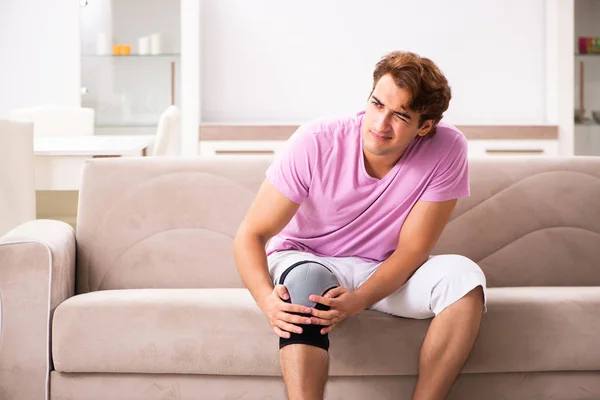 Young man with injured knee recovering at home — Stock Photo, Image