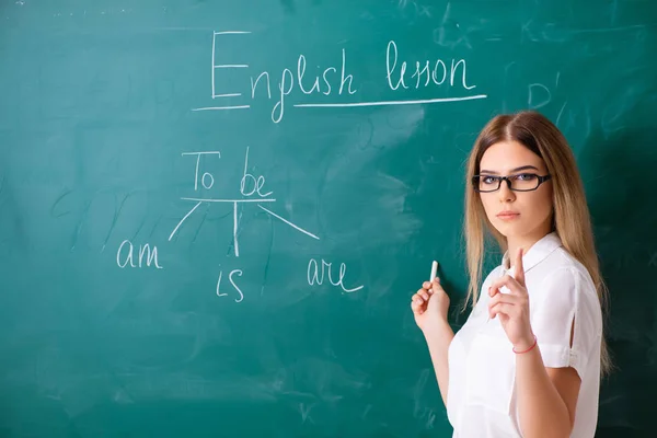 Jonge vrouwelijke Engels leraar staande voor de b — Stockfoto