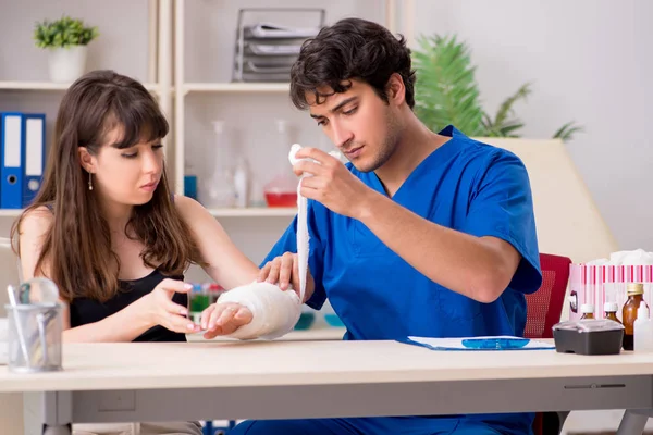 Young woman with bandaged arm visiting male doctor traumotologis — Stock Photo, Image