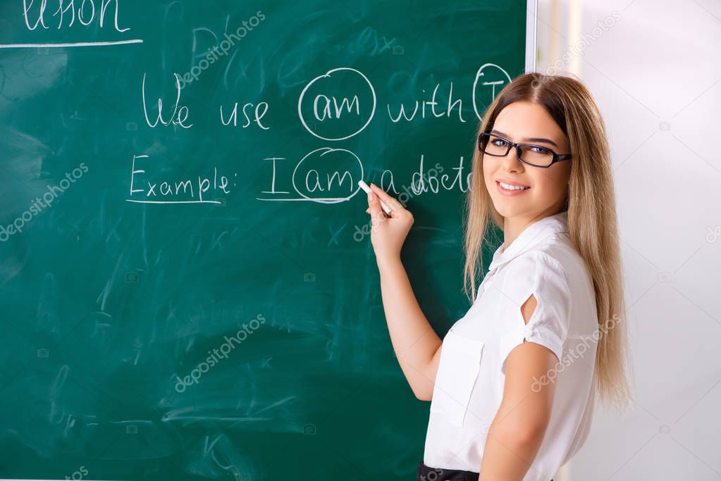 Young female english language teacher standing in front of the b