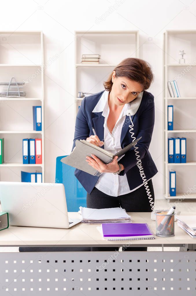 Middle-aged female employee sitting at the office  