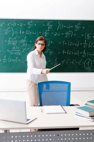 Vrouwelijke wiskundeleraar tegenover het schoolbord — Stockfoto