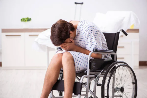 Joven hombre guapo en silla de ruedas en el hospital —  Fotos de Stock