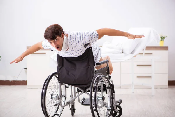 Junger schöner Mann im Rollstuhl im Krankenhaus — Stockfoto