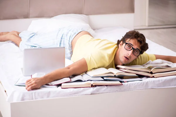 Νεαρός φοιτητής που σπουδάζει στο κρεβάτι για τις εξετάσεις — Φωτογραφία Αρχείου