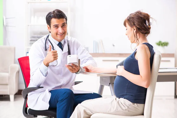 Jovem médico verificando a pressão arterial das mulheres grávidas — Fotografia de Stock