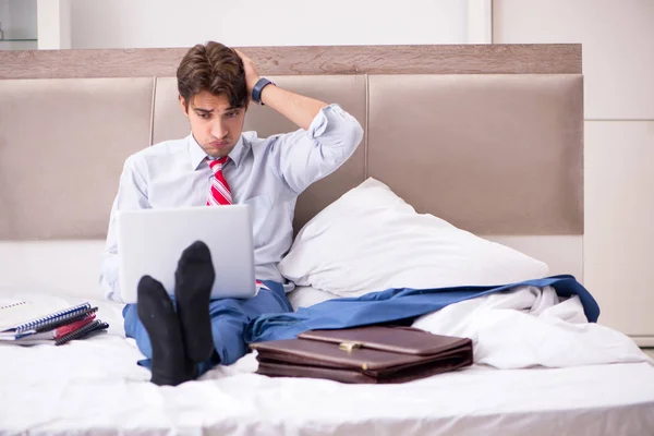 Young employee working at home sitting on the bed — Stock Photo, Image