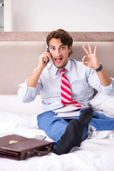 Young employee working at home sitting on the bed — Stock Photo, Image
