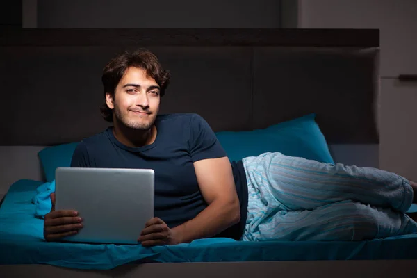 El hombre que trabaja en el ordenador portátil por la noche en la cama —  Fotos de Stock